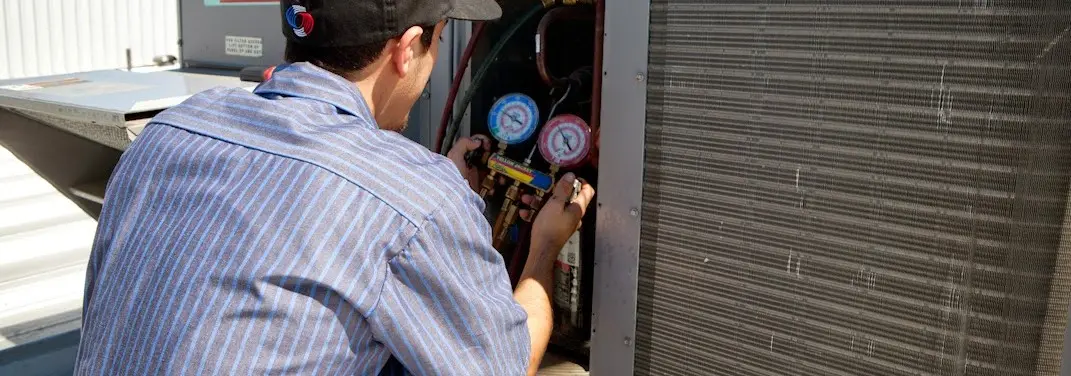 HVAC technician servicing a condenser unit in Kimberly